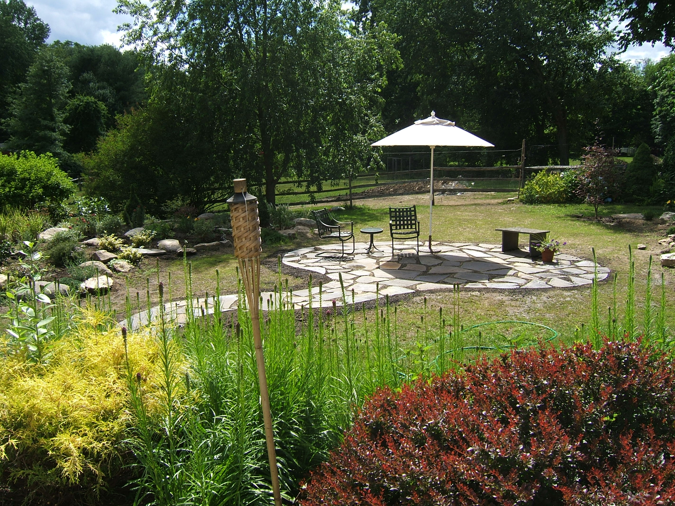 Circular flagstone patio with garden beds from a BREN Landscaping job