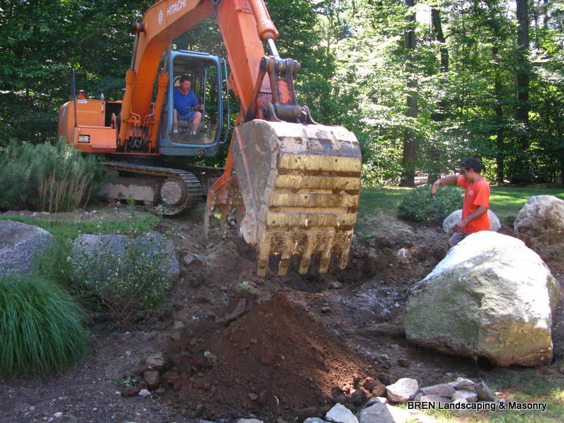 BREN Landscaping crew placing boulders with an excavator on a job site