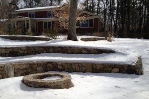 Natural stone fire pit nestled into curve in the wall.  Waiting for spring.